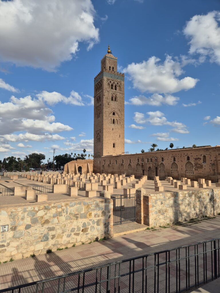 Minarete de la Mezquita Koutoubia de Marrakech rodeado de palmeras al atardecer.