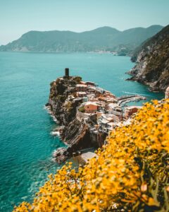 Vista de los acantilados de Cinque Terre con el mar azul de Liguria al fondo, representando la belleza natural y el paisaje costero del norte de Italia.